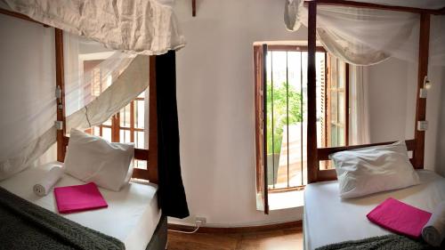 two beds in a room with a window at Stone Town House in Zanzibar City