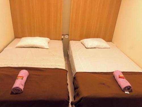 twee bedden naast elkaar in een kamer bij Kangen Yogya Homestay Malioboro Mitra RedDoorz in Yogyakarta