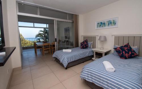 a hotel room with two beds and a balcony at 17 Kyalanga Umhlanga Rocks in Durban