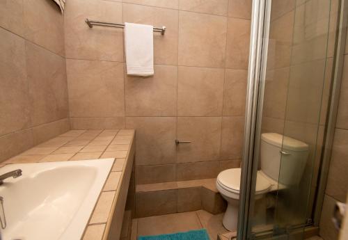 a bathroom with a toilet and a bath tub at 17 Kyalanga Umhlanga Rocks in Durban