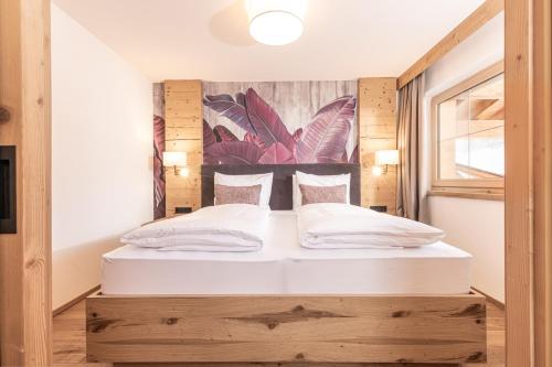 a bedroom with a large bed with a wooden headboard at Galtenberg Bed & Breakfast in Alpbach