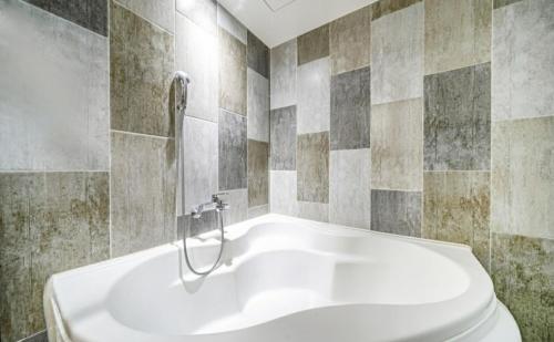 uma banheira branca numa casa de banho com azulejos em Hotel The May em Busan