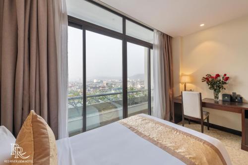 a hotel room with a bed and a desk and a window at Red River View Hotel in Lao Cai
