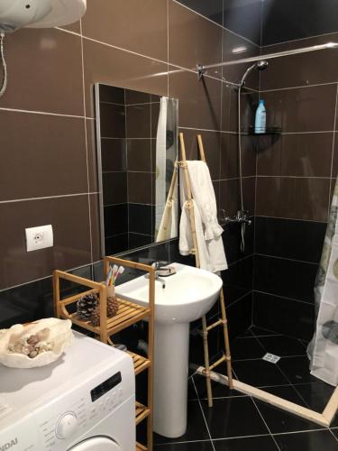 a bathroom with a sink and a washing machine at Hanah Apartment - Gjiri Lalzit Lura 3 in Mullini i Danit