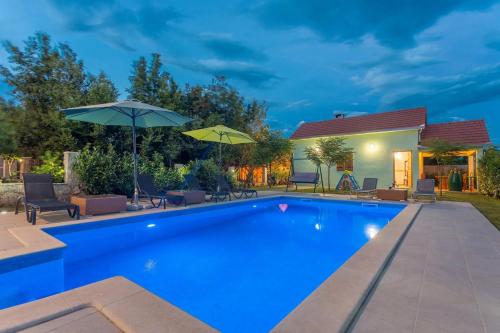 - une piscine avec des parasols à côté d'une maison dans l'établissement Holiday Home Sunrise, à Kraj