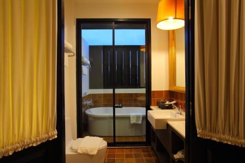 a bathroom with a tub and a toilet and a sink at 99 The Gallery Hotel- SHA Extra Plus in Chiang Mai