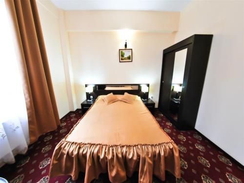 a bedroom with a bed with a brown bedspread at Hotel Magic GT Trivale in Piteşti