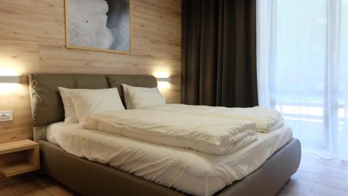 a bed with white sheets and pillows in a room at Poiana Ski Residence Apartment 5 in Poiana Brasov