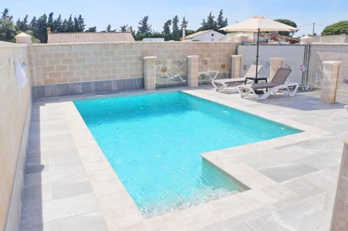 a swimming pool with two chairs and an umbrella at Chalet Puente Tabla in Conil de la Frontera
