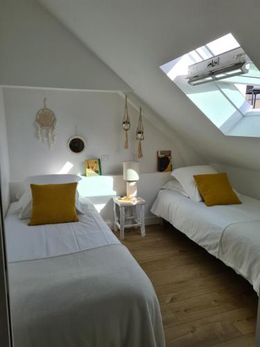 1 Schlafzimmer mit 2 Betten und einem Dachfenster in der Unterkunft Santorin, Appartement lumineux au coeur de Vannes in Vannes