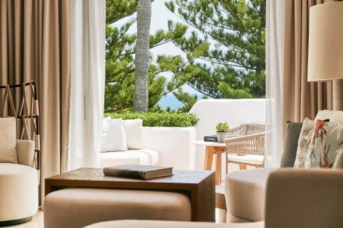 a living room with white furniture and a large window at Puente Romano Marbella in Marbella