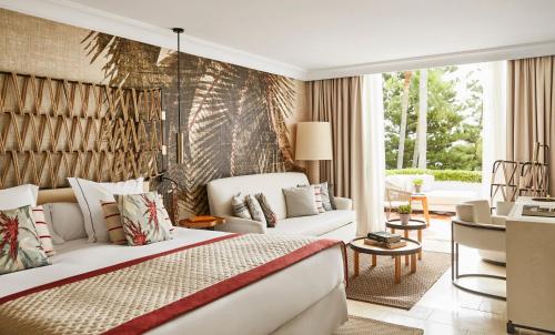 a bedroom with a large bed and a living room at Puente Romano Marbella in Marbella