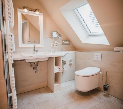 a bathroom with a toilet and a sink and a skylight at Hotel Birke, Ringhotel Kiel in Kiel