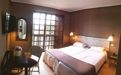 1 dormitorio con cama, mesa y ventana en Hotel Colegiata, en Santillana del Mar