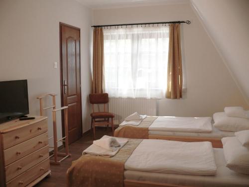 a bedroom with two beds and a tv and a window at Kádárta Vendéglő Panzió in Veszprém