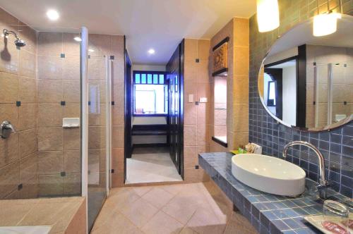 un bagno con lavandino e doccia con specchio di Woraburi Phuket Resort & Spa - SHA Plus a Karon Beach