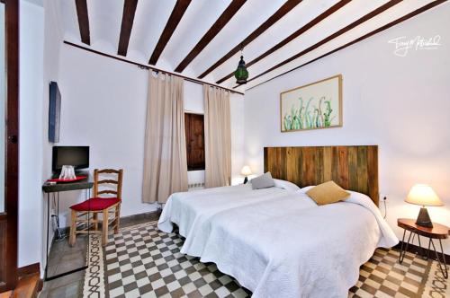 a bedroom with a large white bed and a desk at La Seguiriya in Alhama de Granada