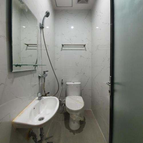 a white bathroom with a toilet and a sink at Circle One in Palembang