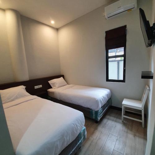 een kamer met 2 bedden, een stoel en een raam bij Circle One in Palembang