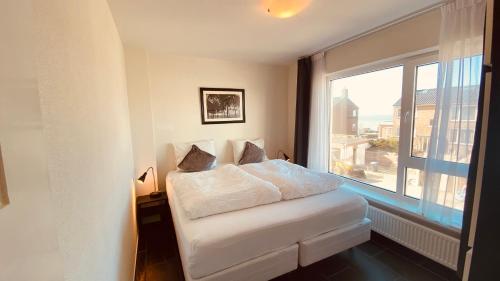 a white bed in a room with a large window at At Juliette in Zandvoort