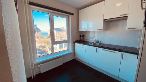 a kitchen with white cabinets and a large window at At Juliette in Zandvoort