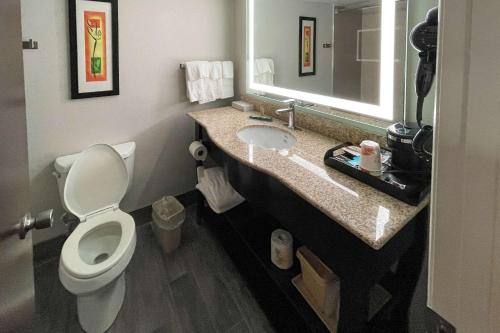 a bathroom with a toilet and a sink with a mirror at Clarion Pointe Near University in Rock Hill