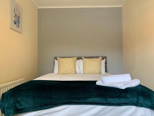 a bedroom with a bed with a green blanket on it at Stay Seaton Delaval in Seaton Delaval