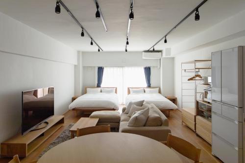 東京にあるNIYS apartments 08 typeのベッド2台、ソファ、テーブルが備わる客室です。