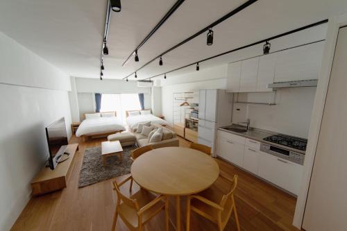 NIYS apartments 08 type في طوكيو: مطبخ وغرفة معيشة مع طاولة وسرير