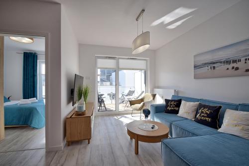 a living room with a blue couch and a table at Apartament Nadmorskie Tarasy SPA Deluxe in Kołobrzeg