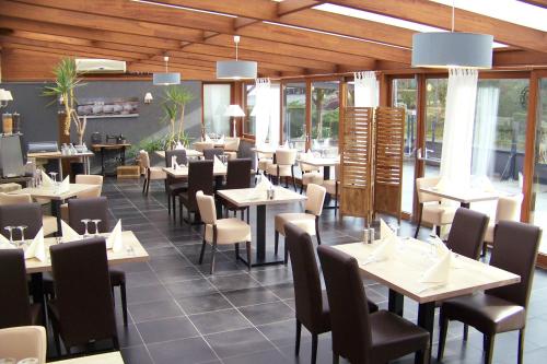 uma sala de jantar com mesas, cadeiras e janelas em Hotel Bal em Tournehem