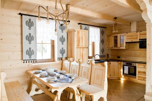 Chaty Mocarnego Szaflary في شافلاري: مطبخ مع طاولة وكراسي خشبية في الغرفة