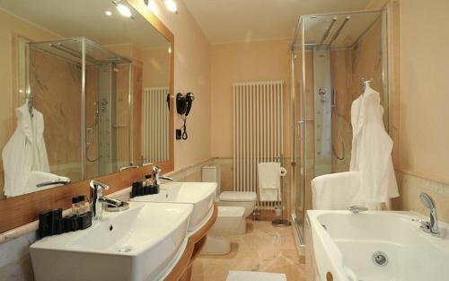 La salle de bains est pourvue de 2 lavabos et d'un grand miroir. dans l'établissement Park Hotel Villa Carpenada, à Belluno
