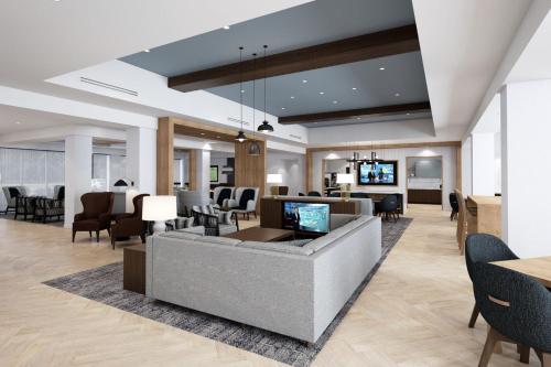 a lobby with a couch and chairs and a television at Staybridge Suites Charlotte Arpt Area - Tyvola by IHG in Charlotte
