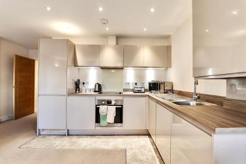 a kitchen with white cabinets and a wooden counter top at Sapphire Serviced Apartment in Chelmsford