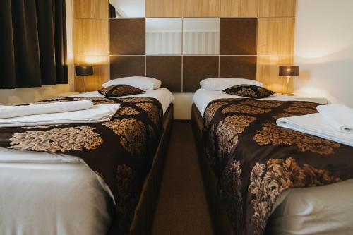 two beds in a hotel room with white towels on them at Hotel Brcko Gas Doboj in Doboj