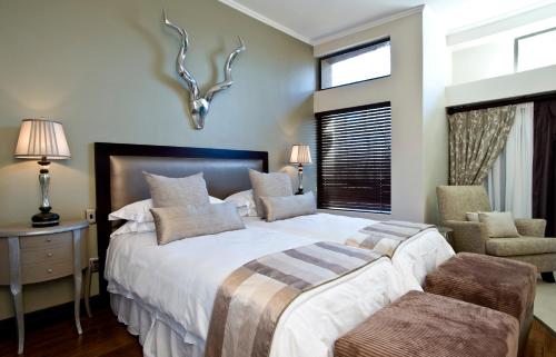 a bedroom with a large bed and a chair at Legend Golf and Safari Resort in Sterkrivier