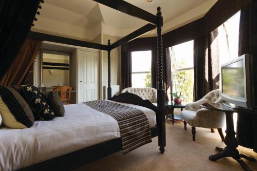 a bedroom with a canopy bed and a television at Stuart House Hotel in Kings Lynn