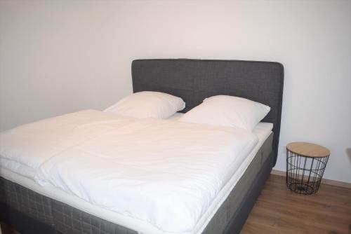 a bed with white sheets and a black headboard at Ferienhaus Marve in Ettenheim