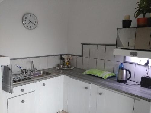 a kitchen with a sink and a clock on the wall at After8 B&B in Kleinbaai