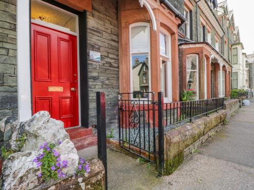 a red door on a brick house with a window at Sefton House in Keswick