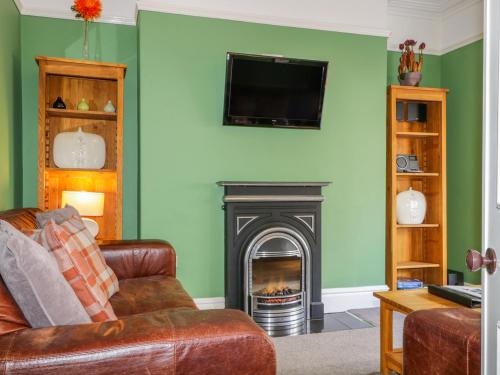 a living room with a fireplace and a television at Sefton House in Keswick