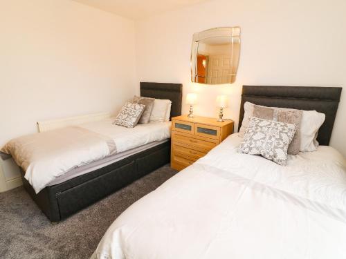 a bedroom with two beds and a mirror on the wall at Old Bridge Inn in Carnforth