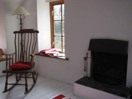 a living room with a chair and a fireplace at Gardeners Cottage in Llanrhyddlad
