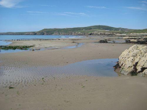 a beach with a large rock and some water at Gardeners Cottage in Llanrhyddlad