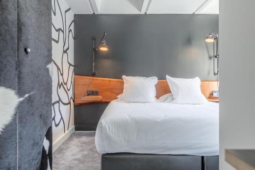 a bedroom with a bed with white sheets and pillows at Totem, Friendly Hotel & Spa in Flaine