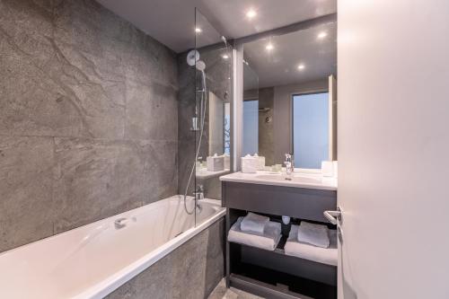 a bathroom with a bath tub and a sink at Totem, Friendly Hotel & Spa in Flaine