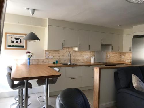 una cocina con armarios blancos y una mesa de madera en una habitación en Corner Cottage en Bewdley