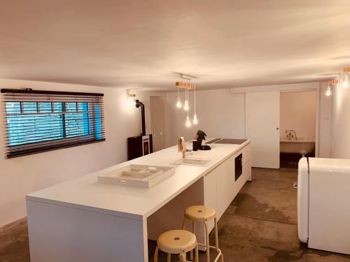 una cocina con encimera blanca y taburetes. en MMGhome en Frasnes-lez-Anvaing