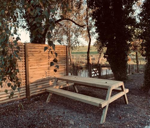 a wooden picnic table sitting next to a fence at MMGhome - Gîte à la ferme in Frasnes-lez-Anvaing